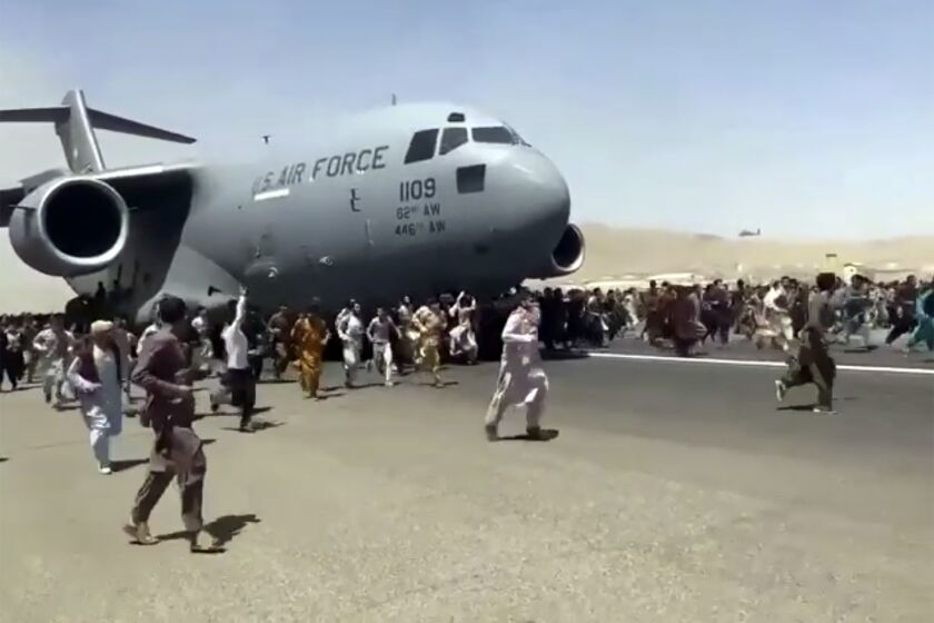 Hundreds of people run alongside a U.S. Air Force C-17 transport plane as it moves down a runway of the international airport, in Kabul, Afghanistan, Monday, Aug.16. 2021. Thousands of Afghans have rushed onto the tarmac at the airport, some so desperate to escape the Taliban capture of their country that they held onto the American military jet as it took off and plunged to death. (AP Photo)