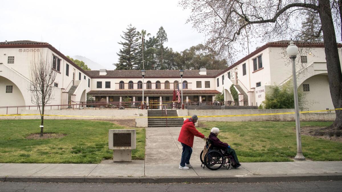 A man pushes a woman in a wheelchair past the Veterans Home of California, the morning after a hostage situation in Yountville, Calif.