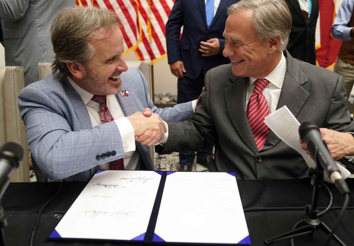 Texas Gov Greg Abbott and State Sen. Bryan Hughes, R-Mineola, shake hands after Abbott signed Senate Bill 1, also known as the election integrity bill, into law in Tyler, Texas, Tuesday, Sept. 7, 2021. The sweeping bill signed Tuesday by the two-term Republican governor further tightens Texas’ strict voting laws. (AP Photo/LM Otero)