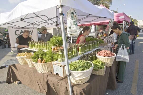 Randy St. Clair, left, Jesse Ramer, center, and Aliya Hashemi are vendors at the Capay Organic farm stand at the Beverly Hills farmers market.