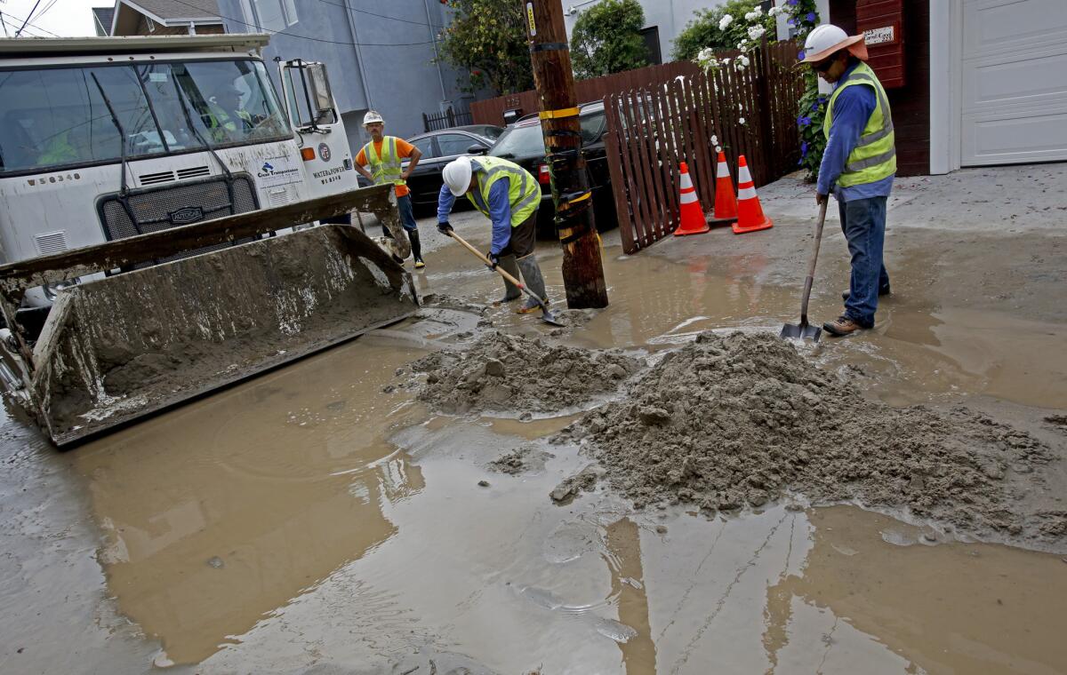DWP workers clear mud as cleanup continues after a water main break about 10:30 p.m. Monday spewed an estimated 100,000 gallons in the the neighborhood around Carroll Canal and Dell Street in Venice.