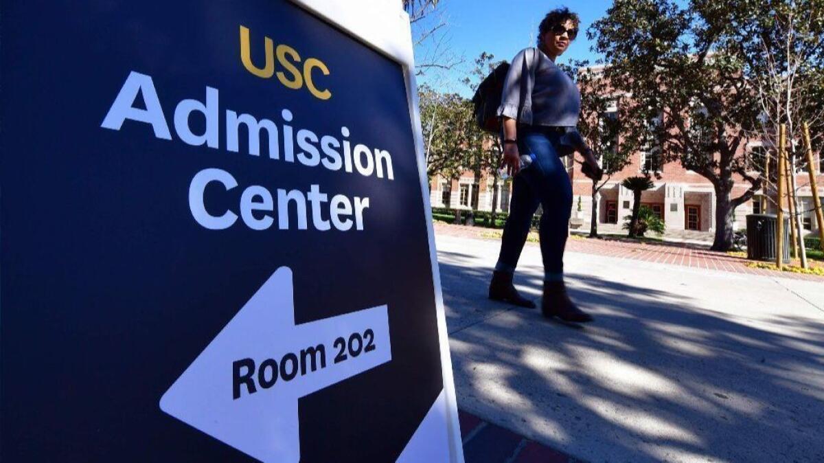 A woman walks past a sign directing people toward the admission center at USC on Wednesday.