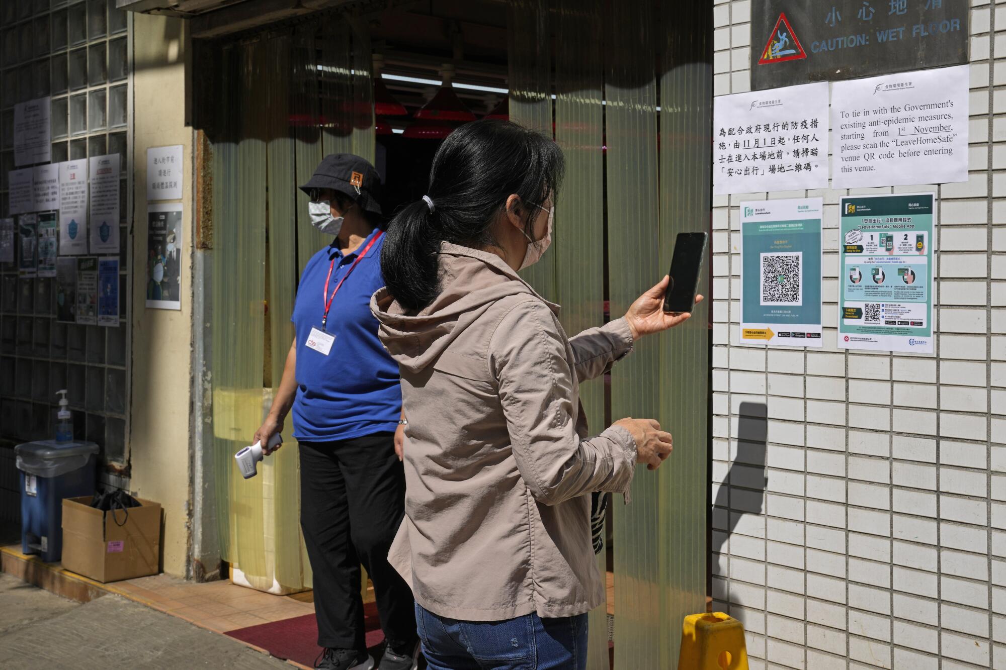 A woman scans a QR code outside a market 