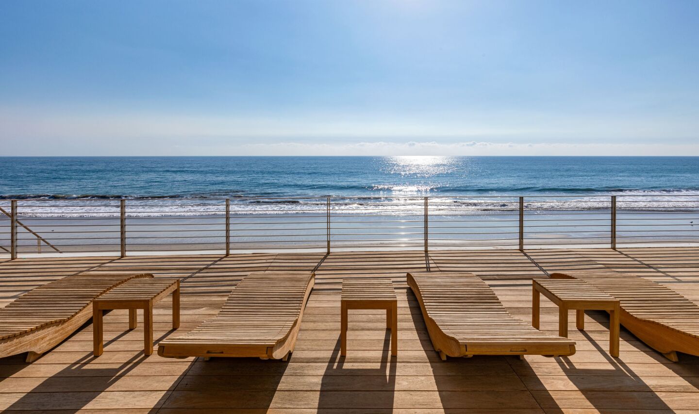 Chaise longues sit on a wooden deck with an uninterrupted view of the surf.
