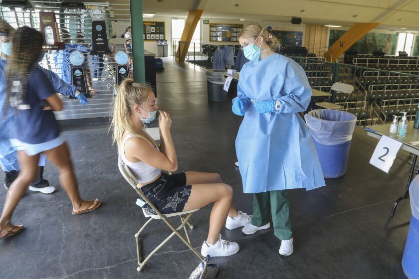 SAN DIEGO, CA - OCTOBER 15: Student Ellie Turk (left) gets a Covid test in the school gym from nursing student Nicole Orth (right) at Point Loma Nazarene University on Thursday, Oct. 15, 2020 in San Diego, CA. (Eduardo Contreras / The San Diego Union-Tribune)