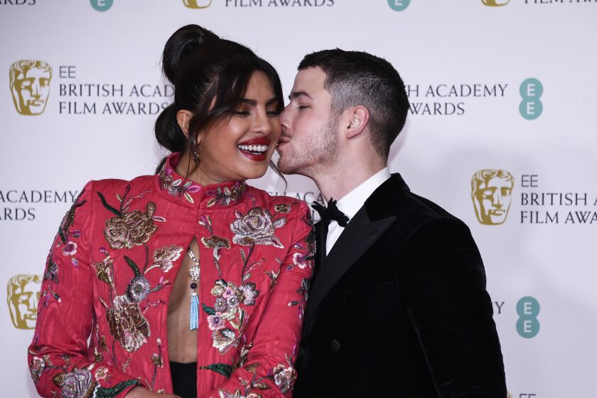 A woman gets a kiss from her husband during red carpet arrivals at an awards show