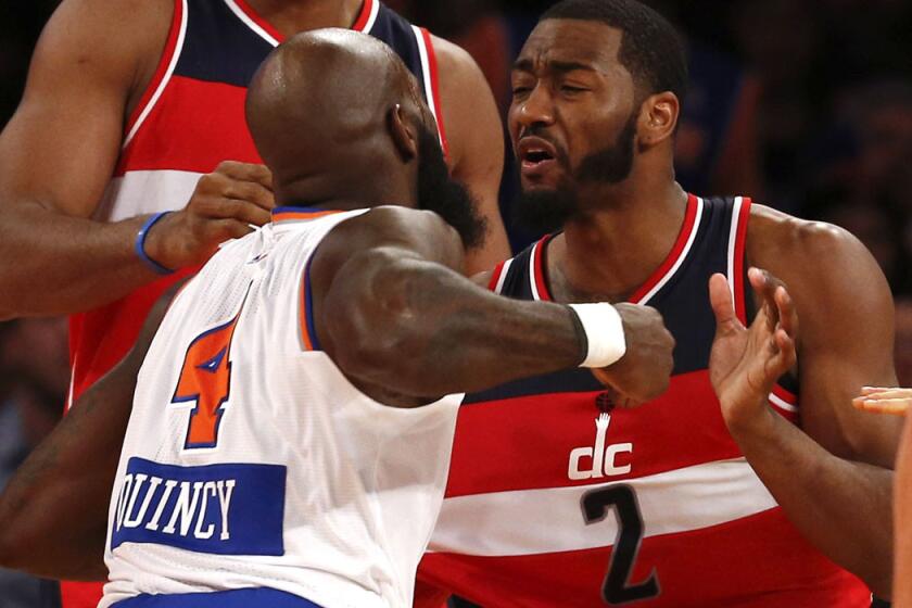 Knicks forward Quincy Acy takes a swing at Wizards point guard John Wall (2) in the fourth quarter of their Christmas Day game at Madison Square Garden.