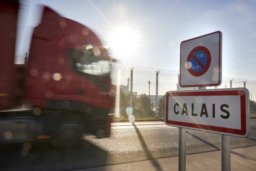3070716_la-fg-brexit-calais CALAIS, FRANCE: Trucks pass the Calais sign on the outskirts of the port of Calais, Calais, France. (Photo by Kiran Ridley)