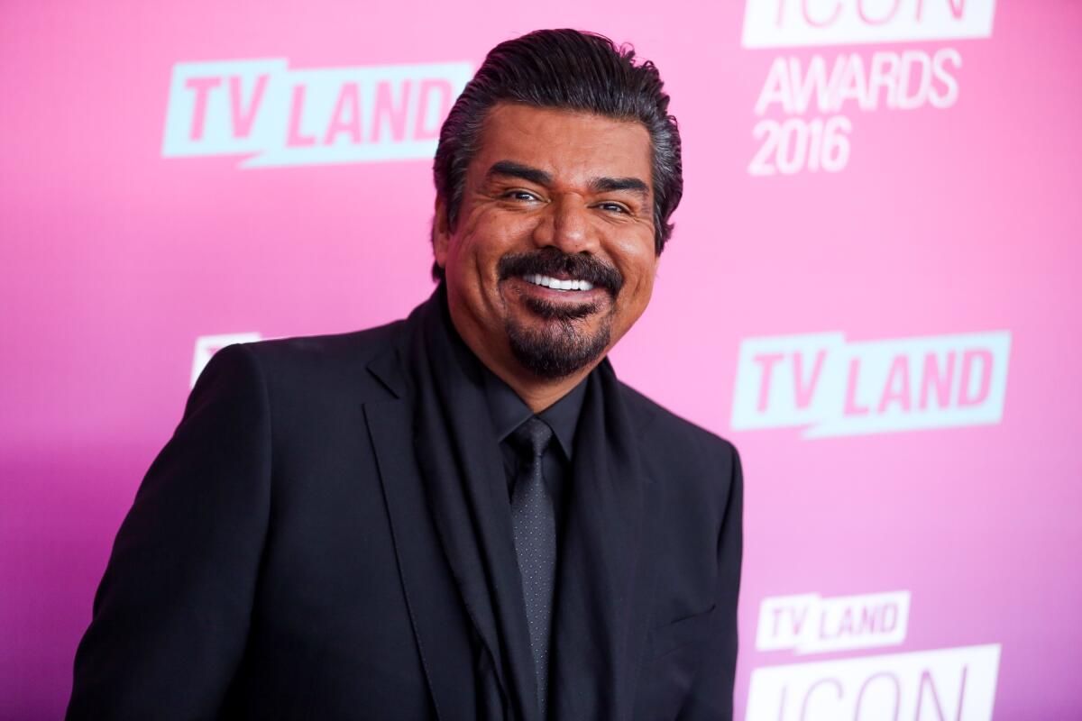 A smiling man with a mustache and goatee wearing a dark suit, shirt and tie.