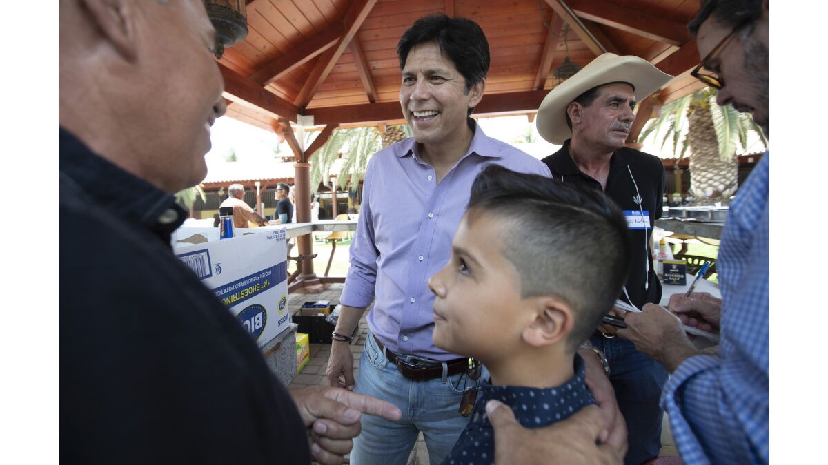 Senate candidate Kevin de Leon chats with David Martinez, left, and Carlitos Valencia, 10, right, at a meet and greet with farmers at a barbecue in Somis.