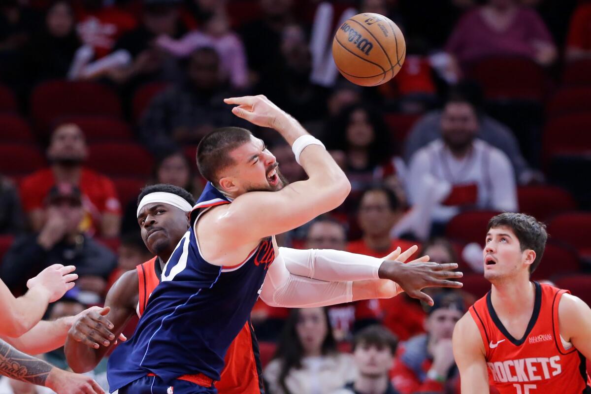 Houston Rockets guard Aaron Holiday knocks the ball away from Clippers center Ivica Zubac as guard Reed Sheppard looks on.
