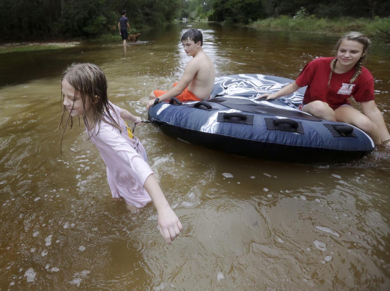 Crimson Peters, 7, left, Tracy Neilsen, 13, center, and Macee Nelson, 15, ride in an inner tube down a flooded street after Hurricane Nate on Oct. 8, 2017, in Coden, Ala.
