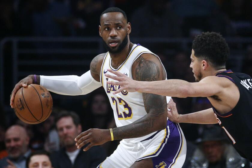 Los Angeles Lakers' LeBron James (23) is defended by Phoenix Suns' Devin Booker (1) during the first half of an NBA basketball game Wednesday, Jan. 1, 2020, in Los Angeles. (AP Photo/Ringo H.W. Chiu)