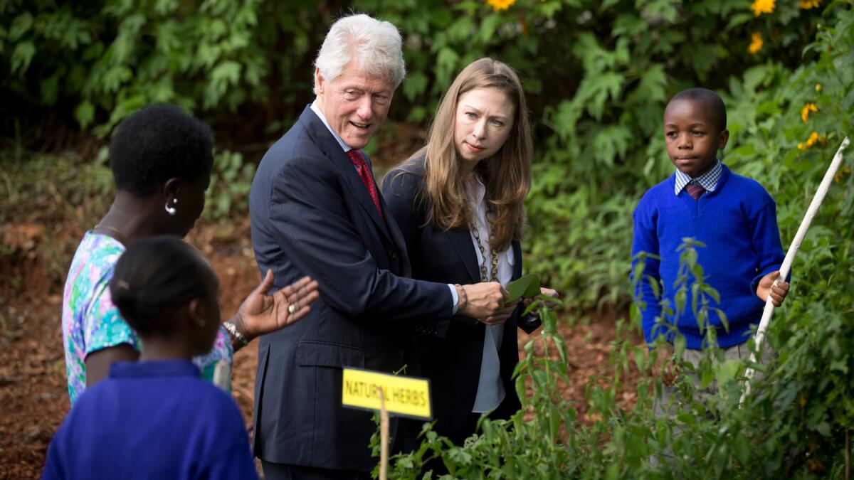Former President Bill Clinton and his daughter Chelsea are shown around an herb garden in May of 2015 by pupils and staff of a school in Nairobi, Kenya that receives support from the Clinton Foundation.