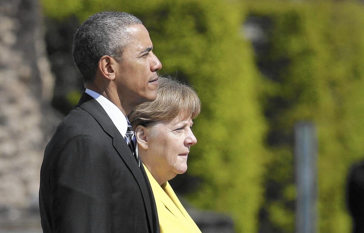 President Obama and his host, German Chancellor Angela Merkel, listen to the national anthems during a welcoming ceremony in Hanover.