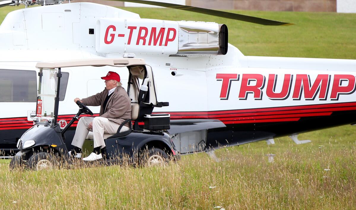 Donald Trump drives a golf buggy past his helicopter on his golf course in Turnberry, Scotland, in July.