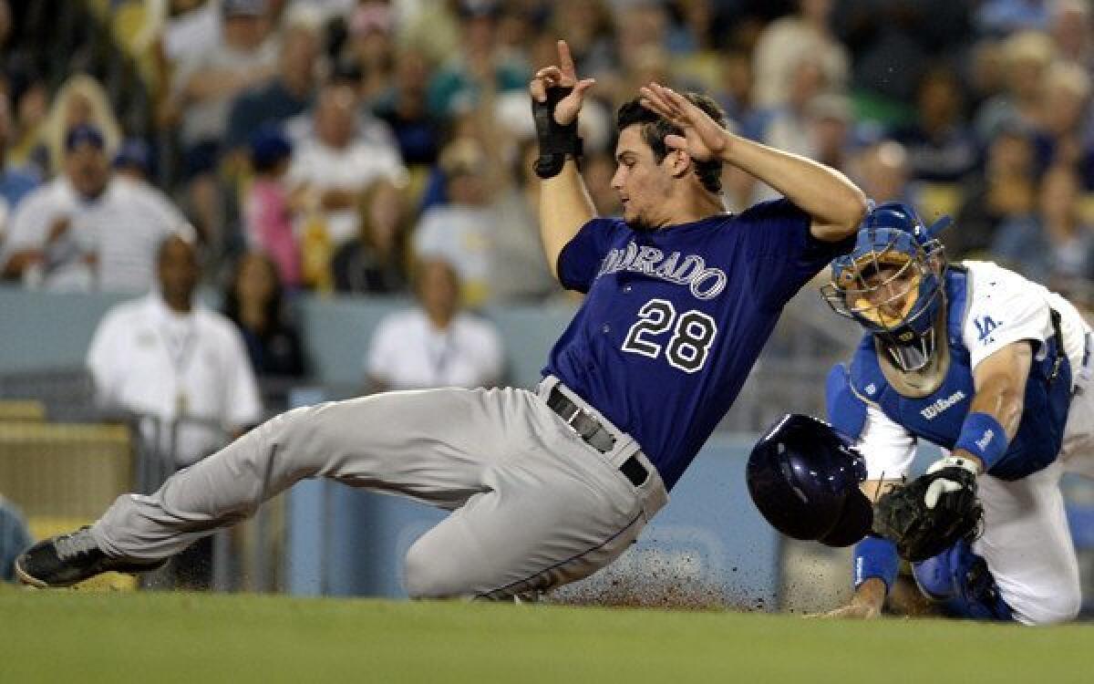 Rockies third baseman Nolan Arenado beats the tag by Dodgers catcher A.J. Ellis to score a run on a hit by D.J. LeMahieu in the fifth inning Friday night at Dodger Stadium.