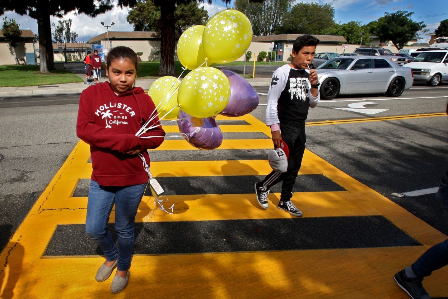 Leslie Corrales, 10, left, and her cousin bring balloons to a makeshift memorial where three 13-year-old girls, two of whom were twins, were killed by a hit-and-run driver Friday evening while they were trick-or-treating in Santa Ana.