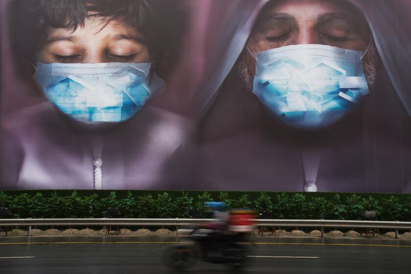 A motorcyclist rides past a billboard in Dubai, United Arab Emirates, that urges residents to stay home amid the pandemic.