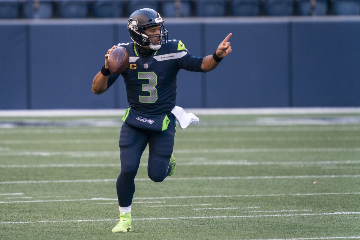 Seattle Seahawks quarterback Russell Wilson gestures down field while scrambling.