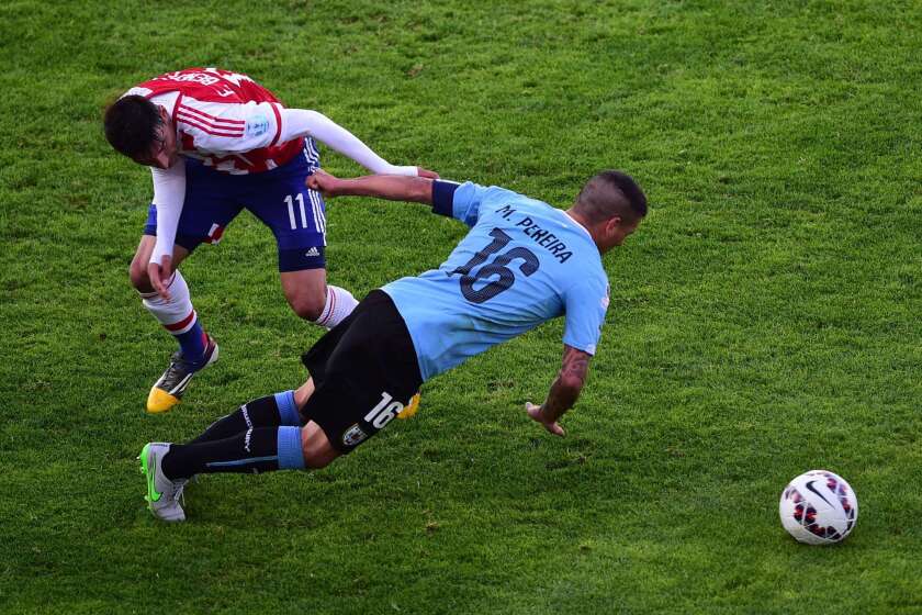 El uruguayo Maximiliano Pereira (der) es frenado por el paraguayo Edgar Benítez.