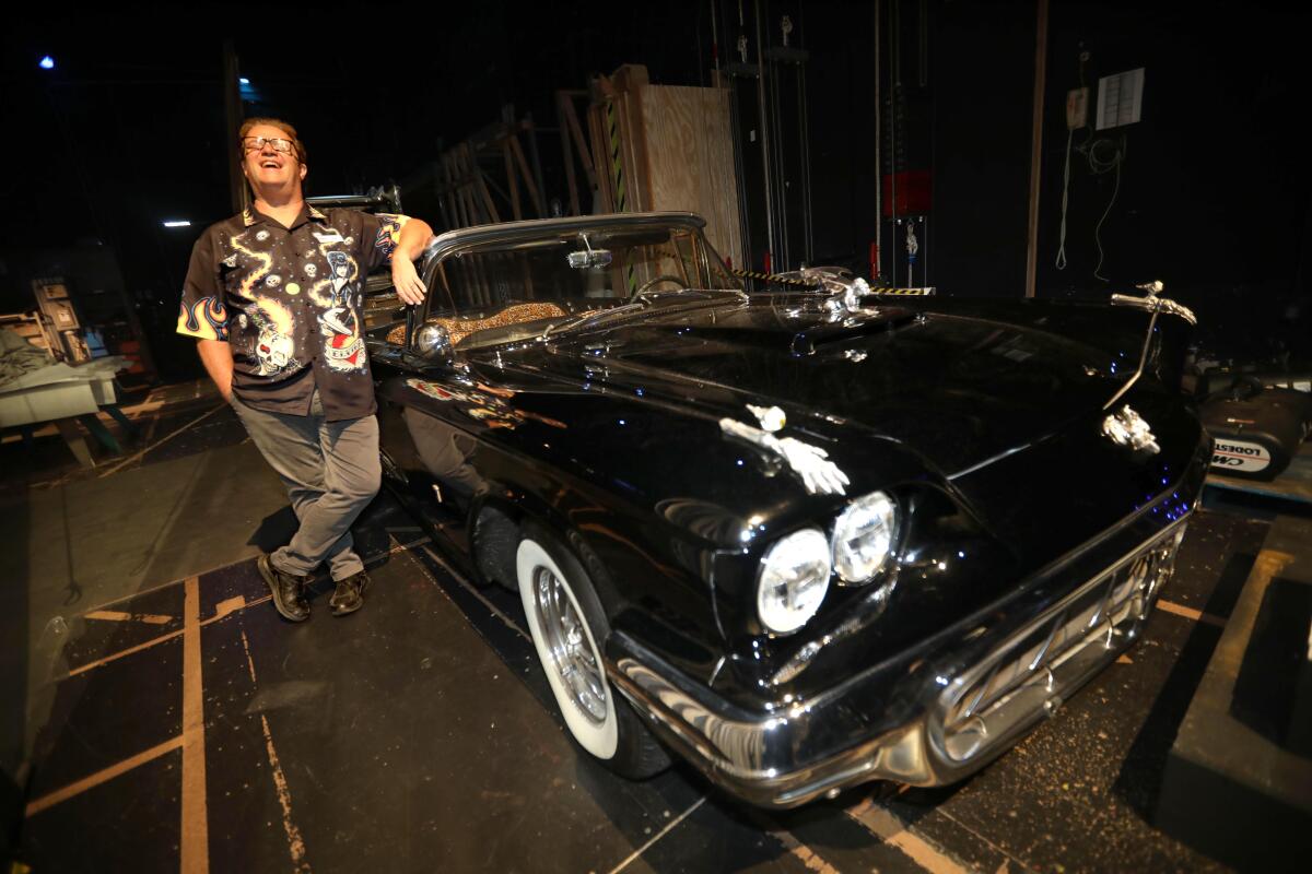 man standing next to a black 50s car