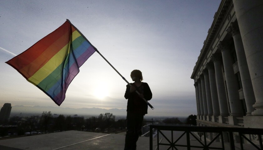 Corbin Aoyagi, a supporter of same-sex marriage, waves a rainbow flag during a rally at the Utah State Capitol in Salt Lake City.