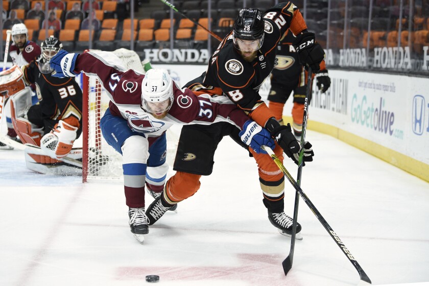 Colorado Avalanche left wing J.T. Compher, left, lunges for the puck against Anaheim Ducks defenseman Jani Hakanpaa during the first period of an NHL hockey game in Anaheim, Calif., Friday, April 9, 2021. (AP Photo/Kelvin Kuo)