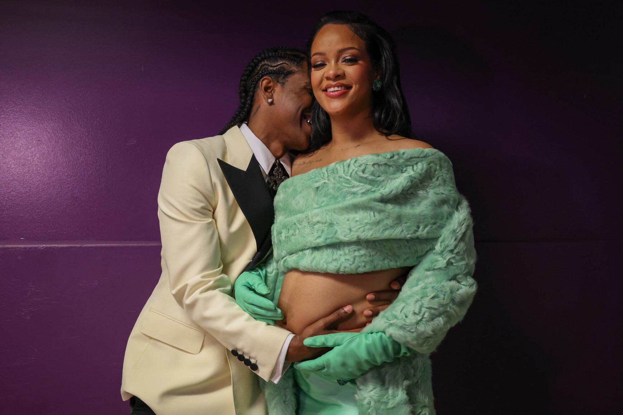 A man cuddles a pregnant woman backstage at the Academy Awards.