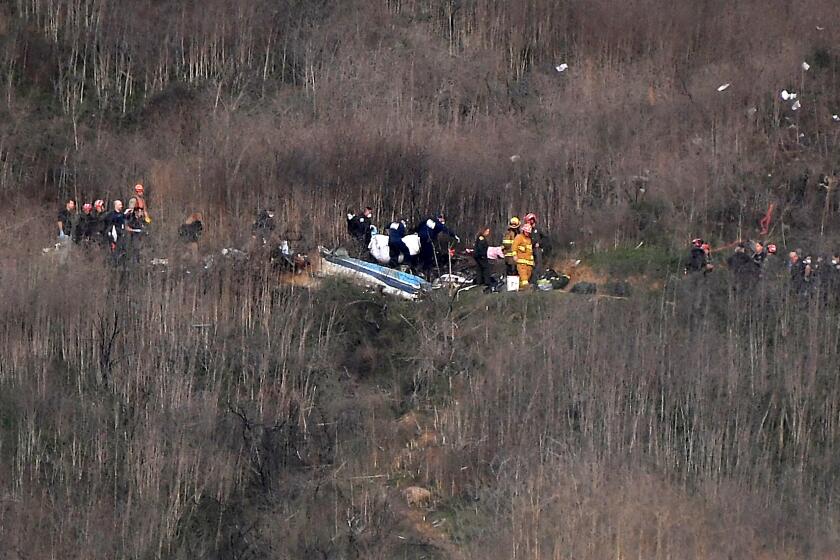 Officials remove a body from the wreckage in Calabasas on Sunday where Kobe Bryant and his daughter Gianna were among 9 dead in a helicopter crash. (Christina House / Los Angeles Times)