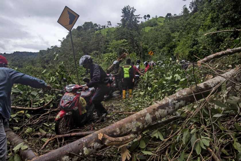 Motorists make their way through a road affected by an earthquake-triggered landslide near Mamuju, West Sulawesi, Indonesia, Saturday, Jan. 16, 2021. Damaged roads and bridges, power blackouts and lack of heavy equipment on Saturday hampered Indonesia's rescuers after a strong and shallow earthquake left a number of people dead and injured on Sulawesi island. (AP Photo/Yusuf Wahil)