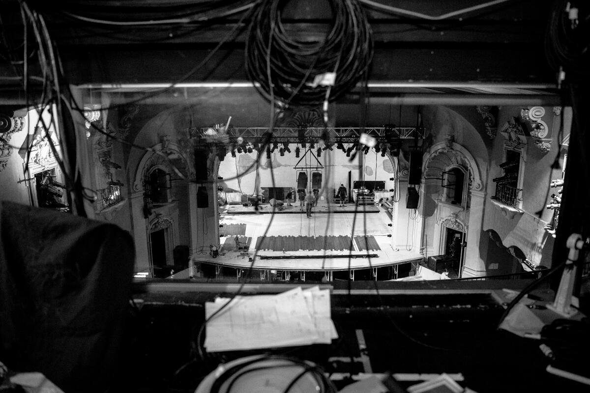 Wires hang in the foreground as an indoor stage is seen at a distance below.