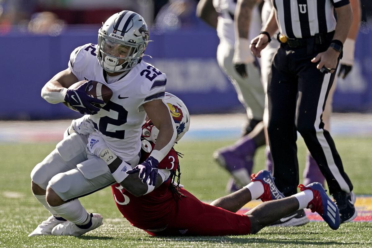 Kansas State running back Deuce Vaughn (22) is tackled by Kansas safety Ricky Thomas Jr. (3) during the first half of an NCAA football basketball game Saturday, Nov. 6, 2021, in Lawrence, Kan. (AP Photo/Charlie Riedel)