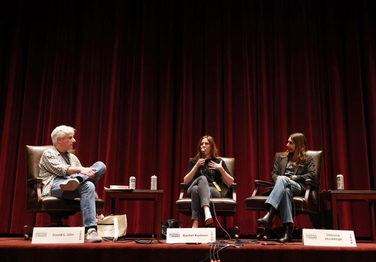 A male moderator and two female guests sit in chairs onstage during a Festival of Books discussion.