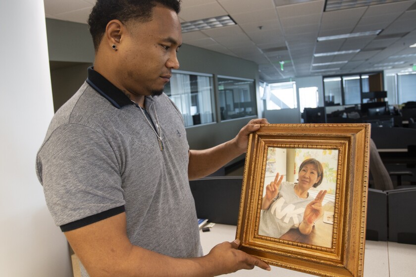 Robert Peterson holds a photo of his late mother, Yong Ae Yue, on Thursday, March 10, 2022, in Atlanta. Yue was one of eight people shot and killed at various massage businesses on March 16, 2021, in the Atlanta area. Many family members and friends of the victims have been struggling with grief, trying to heal and making sure their loved ones aren't forgotten. (AP Photo/Ron Harris)