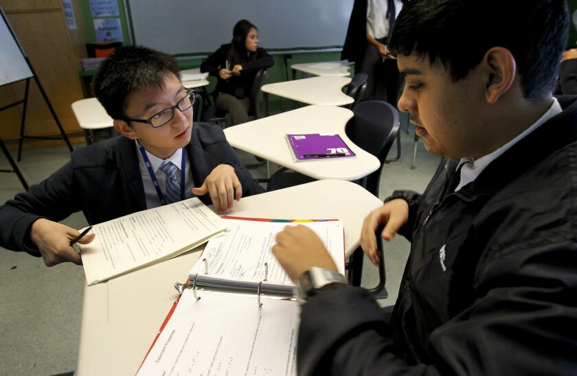 Teacher Jonathan Oh, left, works with 11th graders at Gompers Preparatory Academy in East San Diego.