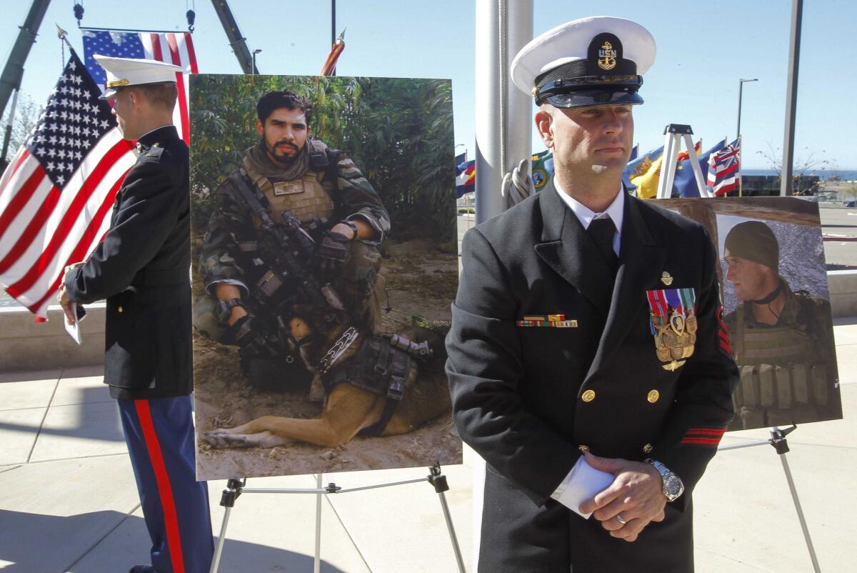 Navy Chief Petty Officer Justin Wilson stands in front of pictures of Marine Staff Sgt. Christopher Diaz, left, and Staff Sgt. Nicholas Sprovtsoff during a Nov. 25 awards ceremony at Camp Pendleton.