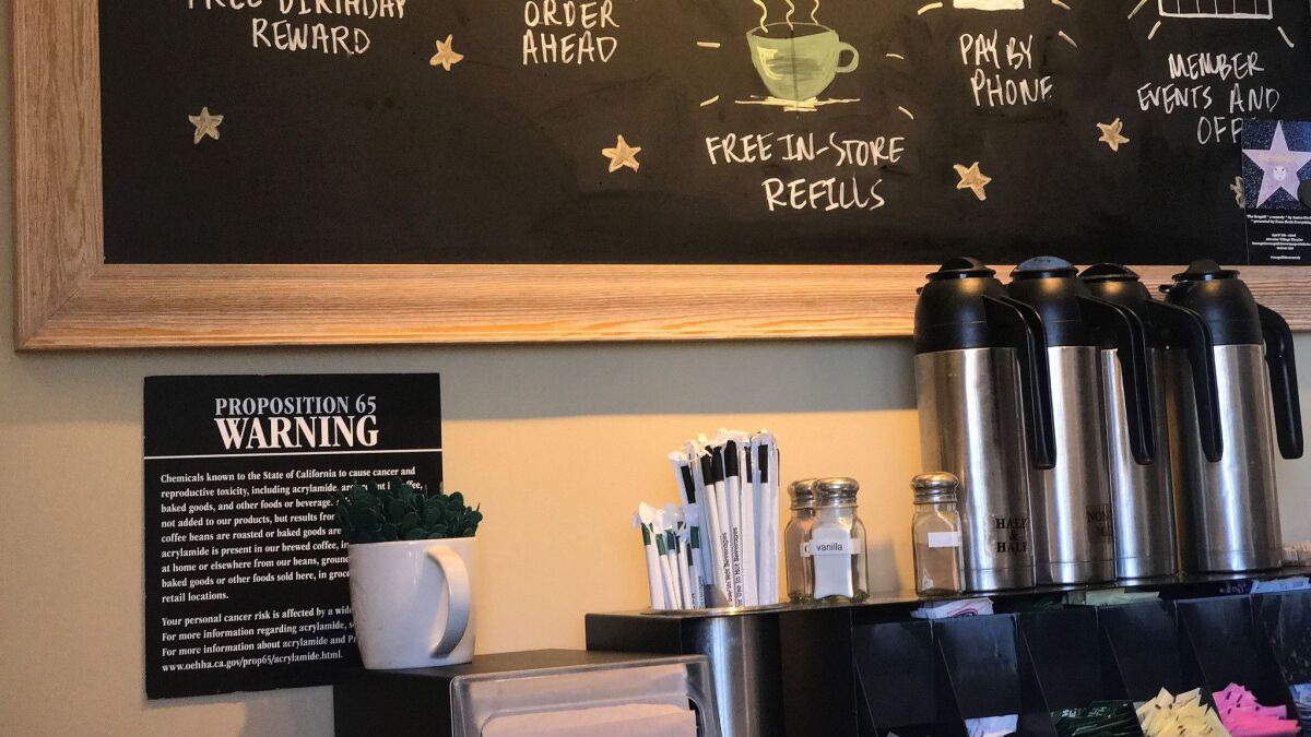A posted Proposition 65 warning sign is seen behind a coffee mug at a Starbucks coffee shop in Burbank, Calif.