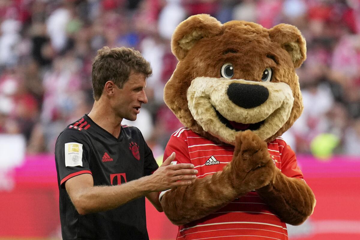 Bayern's Thomas Mueller, left, talks with the team mascot Bernie at the end of the German Bundesliga soccer match between FC Bayern Munich and VfL Wolfsburg in Munich, Germany, Sunday, Aug. 14, 2022. Bayern won 2-0. (AP Photo/Matthias Schrader)