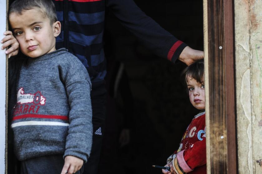 Syrian refugees look out from their shelter in Hatay, Turkey.