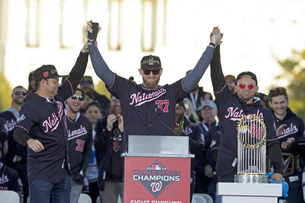 Washington Nationals pitcher and World Series MVP Stephen Strasburg, celebrates the World Series baseball championship during a rally following a parade to celebrate the team's World Series baseball championship over Houston Astros, Saturday, Nov. 2, 2019, in Washington. Nationals right fielder Gerardo Parra is right and pitcher Anibal Sanchez, left. (AP Photo/Jose Luis Magana)