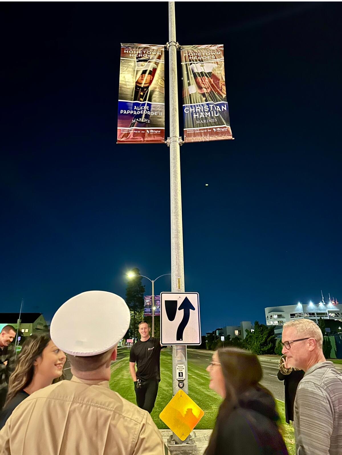 U.S. Marine Alexe Pappageorge Jr., foreground left, looks up at his "hometown hero" banner on Wednesday night.