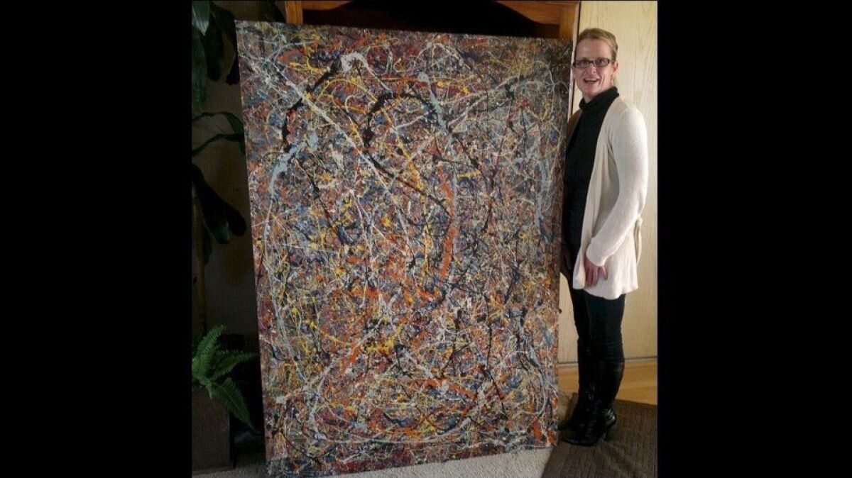 Renée Poissant stands next to the 66-by-48-inch painting that her late friend Teri Horton believed is an original by Jackson Pollock, an abstract expressionist who was known for his “drip and splash” style.