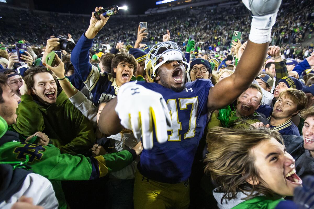 Notre Dame defensive lineman Jason Onye celebrates with students on the field after a 48-20 win.