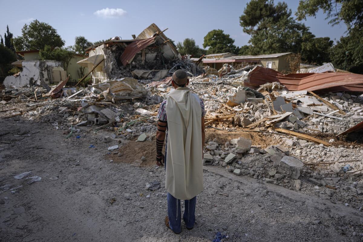 An Israeli man prays next to houses destroyed by Hamas militants in Kibbutz Be'eri, Israel, on Oct. 22. 