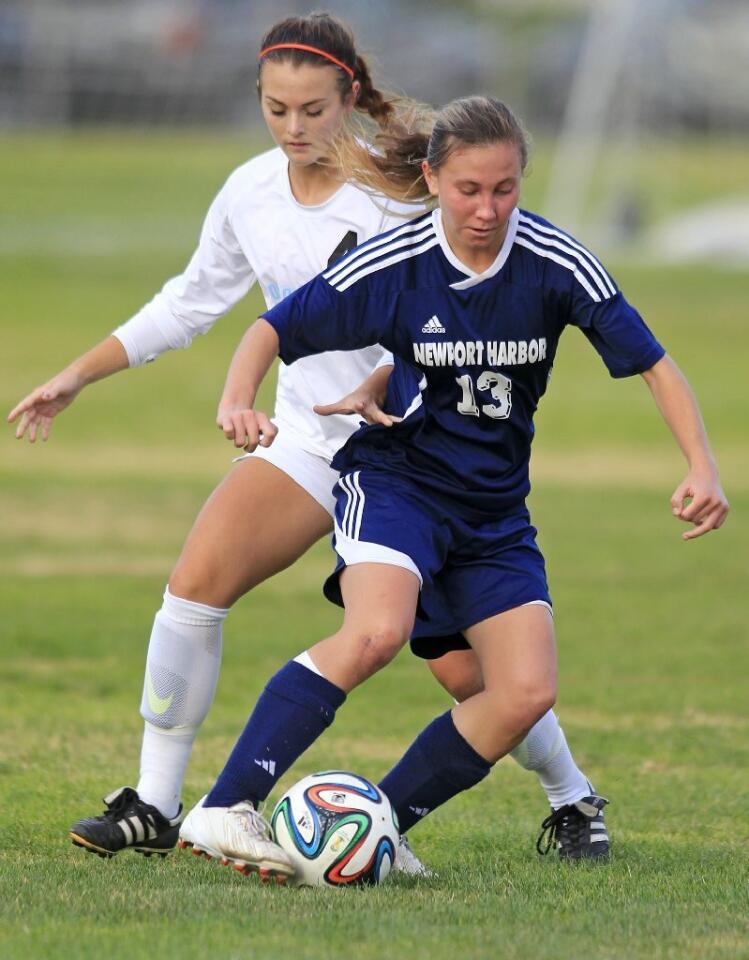 Newport Harbor High's Toni Holland (13) dribbles the ball against Corona del Mar's Birkley Sigband during the first half in the Battle of the Bay match on Tuesday.