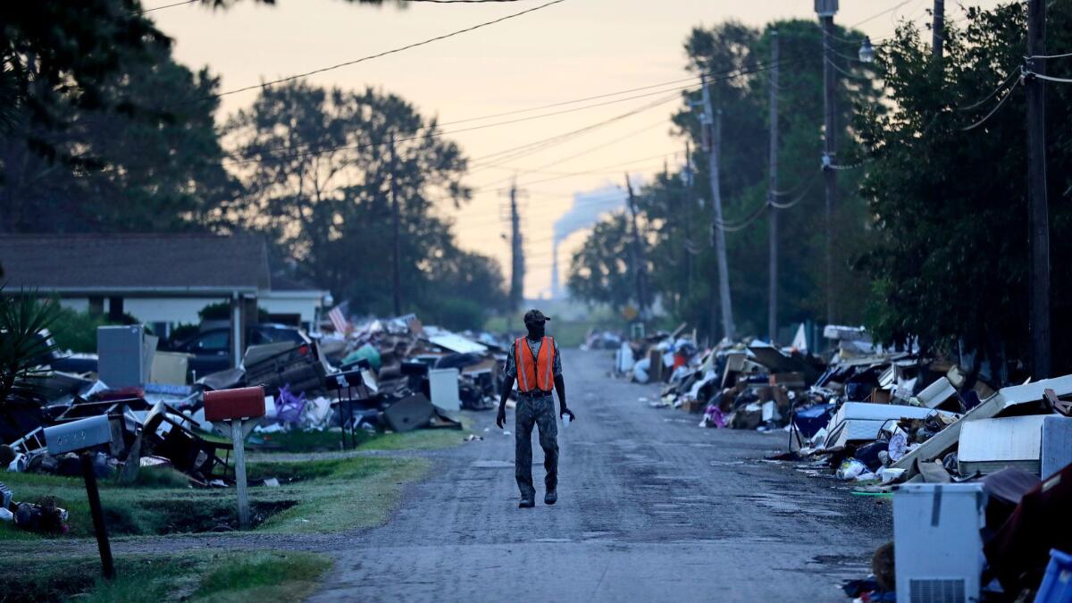 A man walks past debris from homes on his street in Port Arthur, Texas, damaged in flooding from Hurricane Harvey in September.
