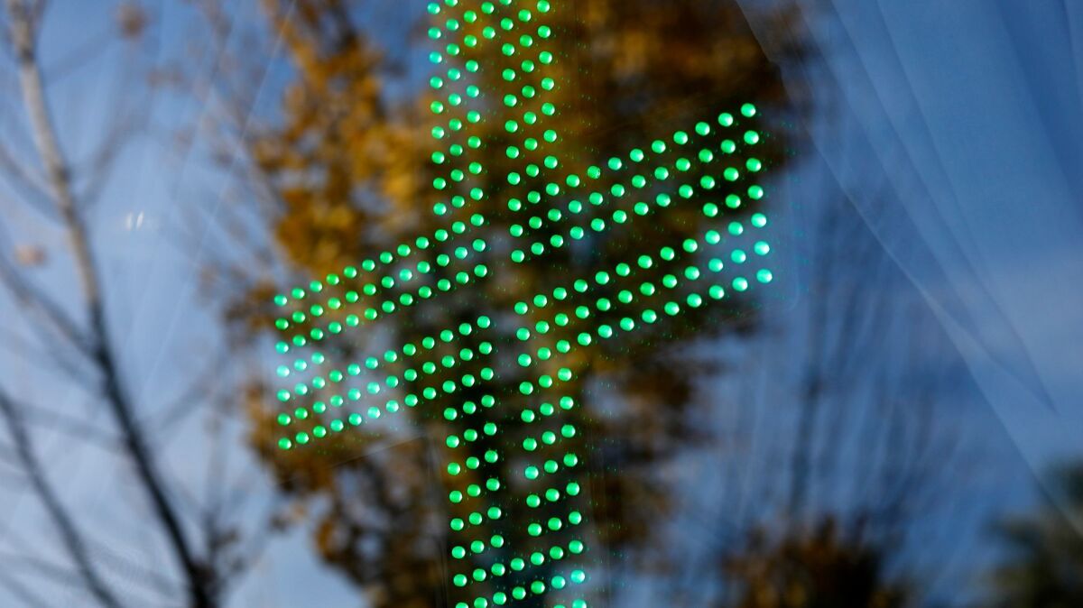 The green cross is lit in the window of The Higher Path marijuana dispensary in Sherman Oaks.