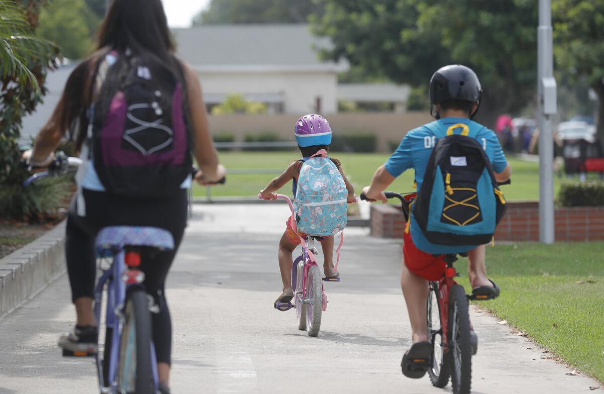 Siblings ride away with new backpacks.