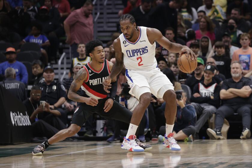 Los Angeles Clippers' Kawhi Leonard dribbles the ball with Portland Trailblazers' Anfernee Simons defending during the first half of a preseason NBA basketball game, Monday, Oct. 3, 2022, in Seattle. (AP Photo/ John Froschauer)